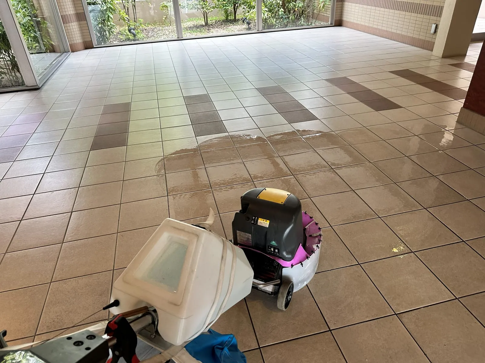 室内の床をポリッシャーで洗浄する作業員